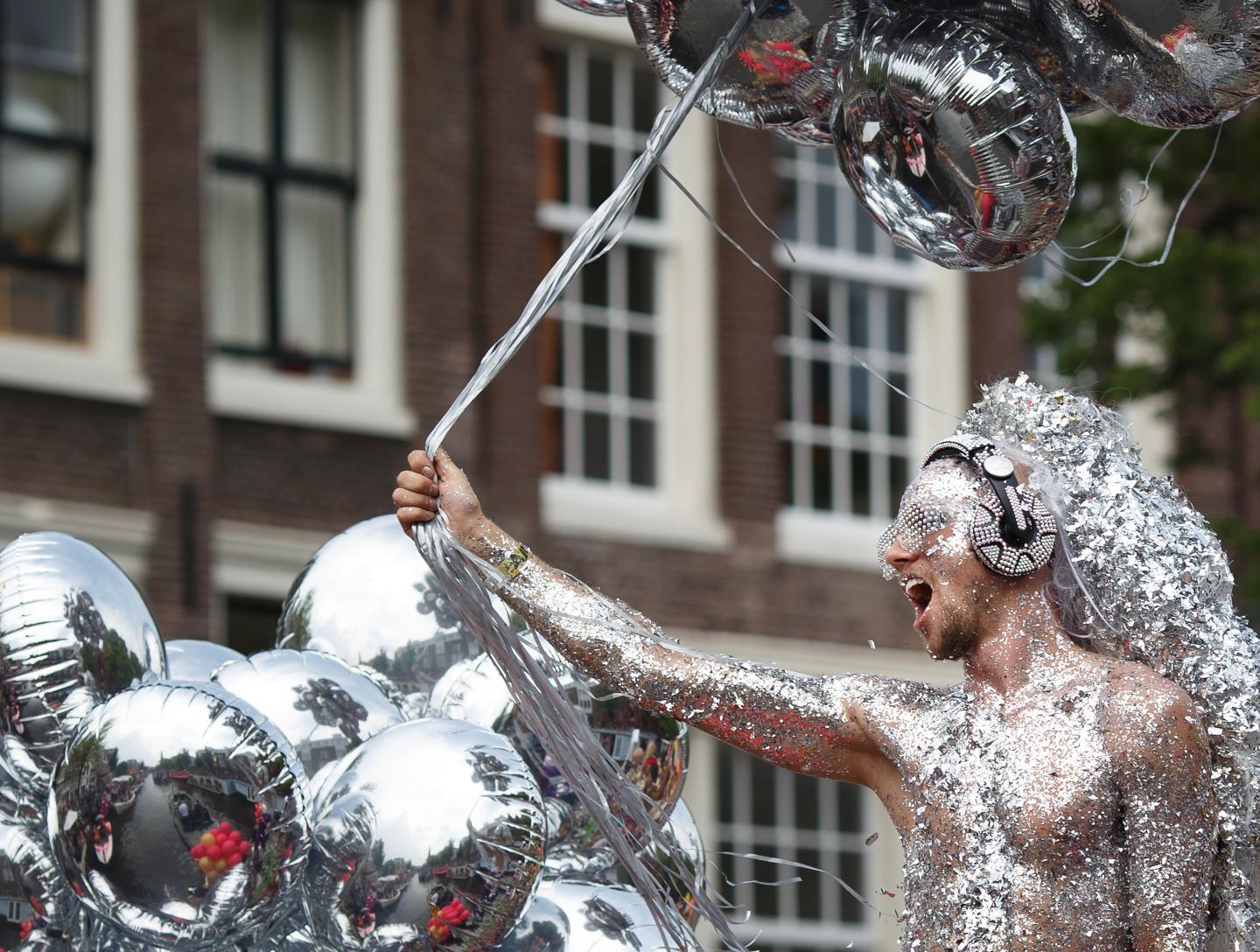 A shirtless man at a Pride parade covered in silver glitter