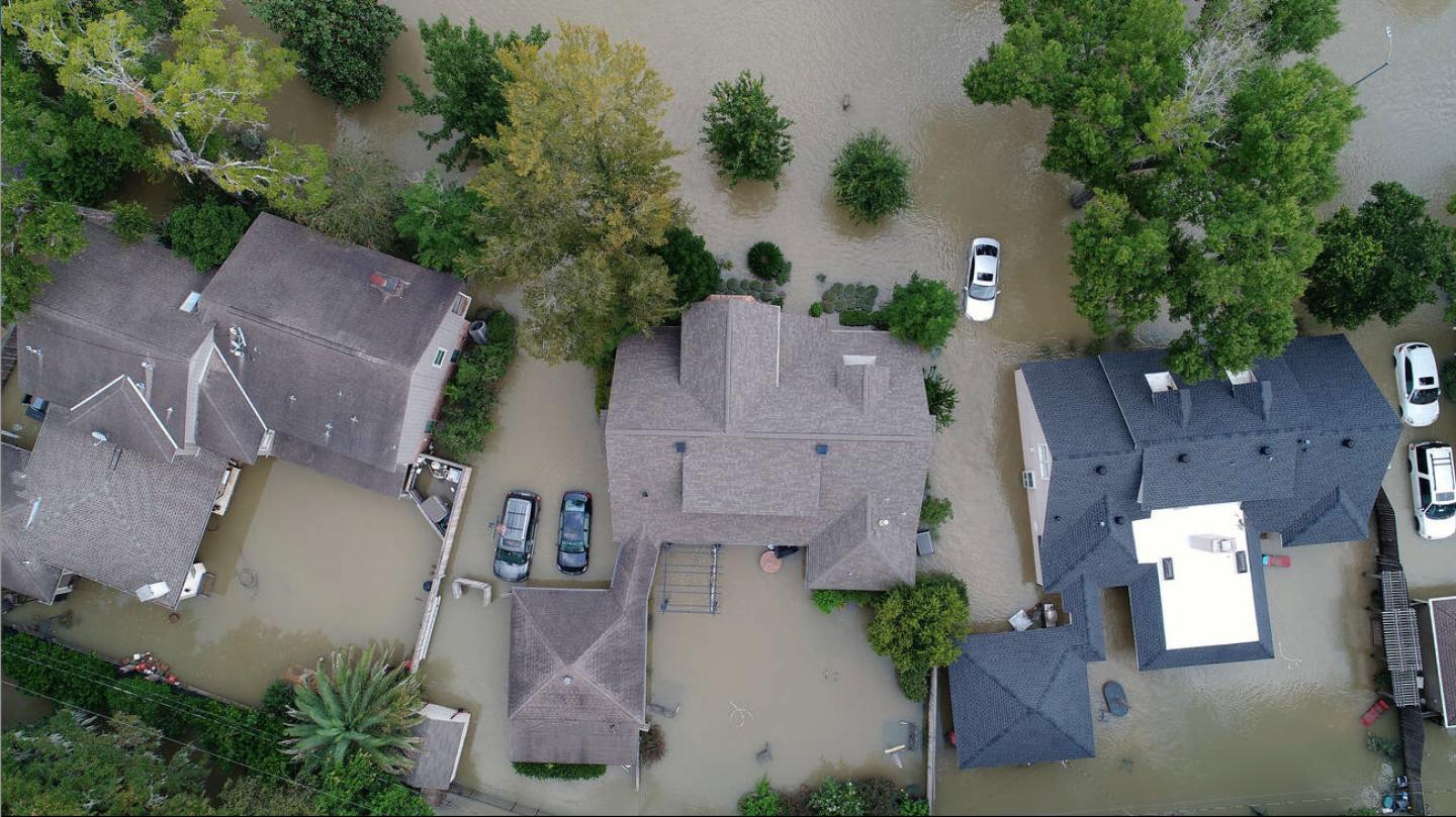 An aerial shot of houses submerged and surrounded by flood waters