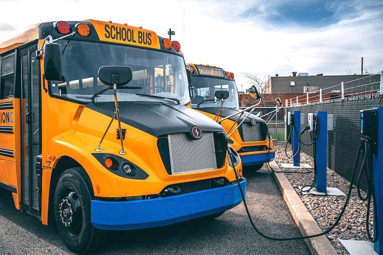 A row of electric school buses plugged in