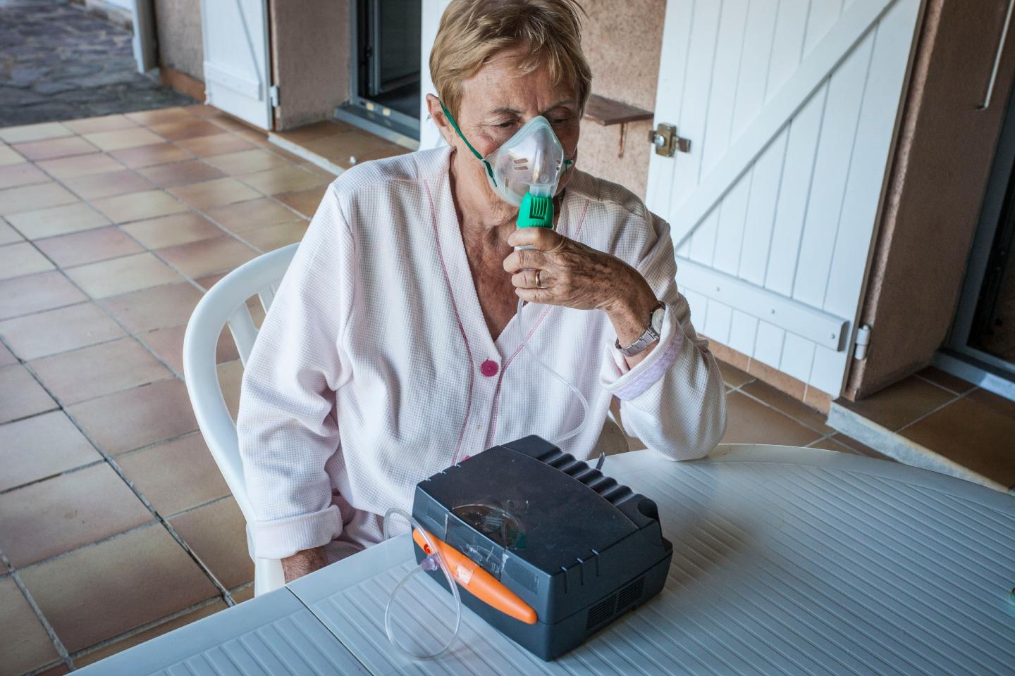 A person using an at home nebulizer inhalation system to treat asthma