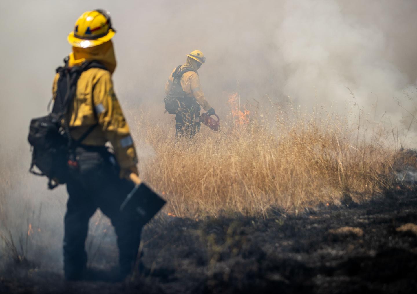 Two firefighters observing a controlled fire