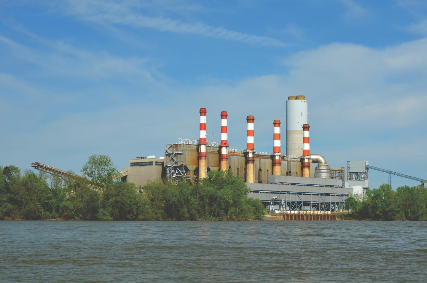 A Duke Energy facility with red and white smokestacks along a river