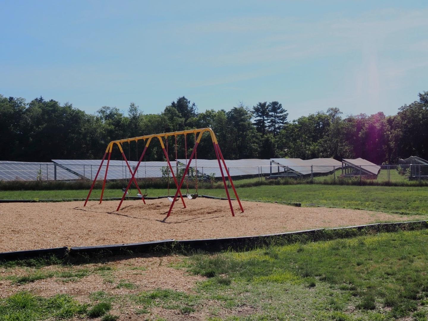 A solar panel array behind a swing set playground