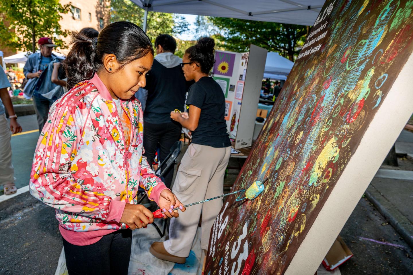 A young girl painting a at a street fair during New York City Climate Week