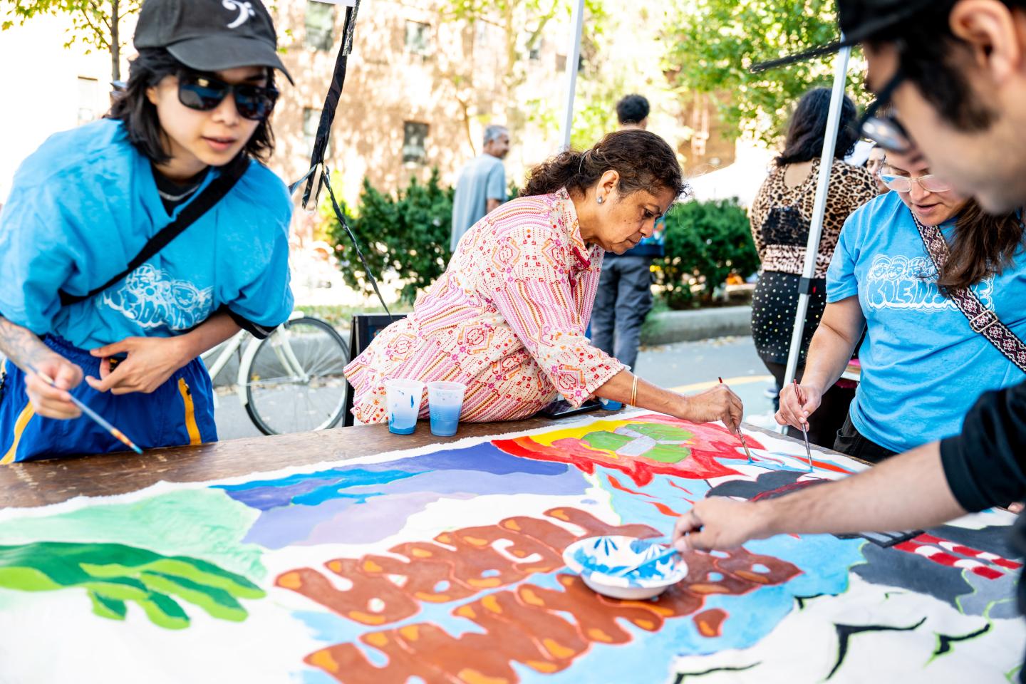 A group of people painting a banner at a Climate Week street fair event