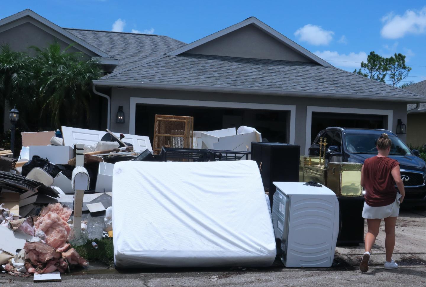 A pile of household items, including a mattress, line a curb after flood waters damaged a house