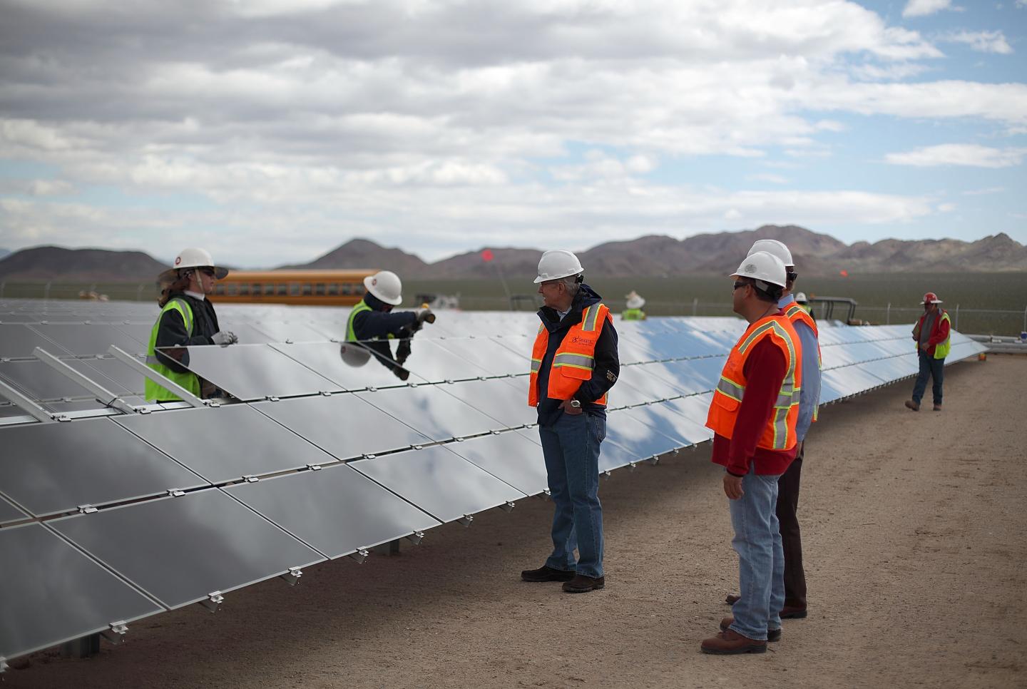 Workers in vests and hard hats installing solar panels