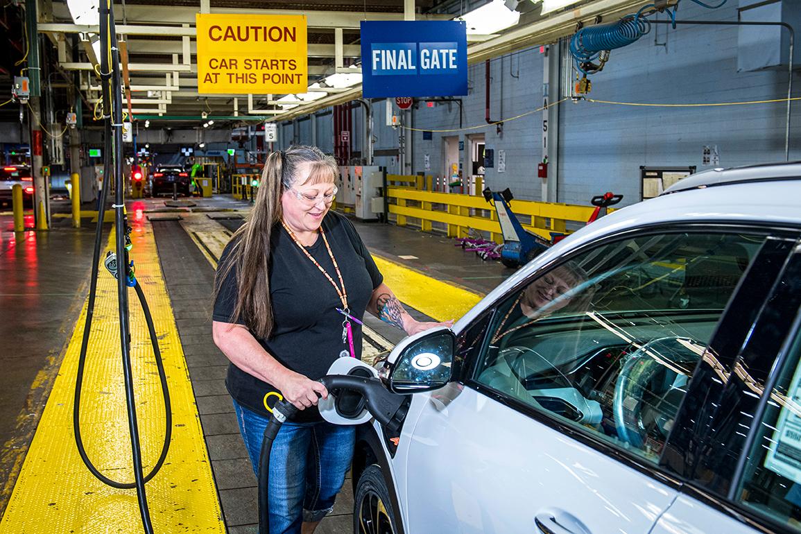 A woman charging a Chevy Volt in a General Motors assembly plant