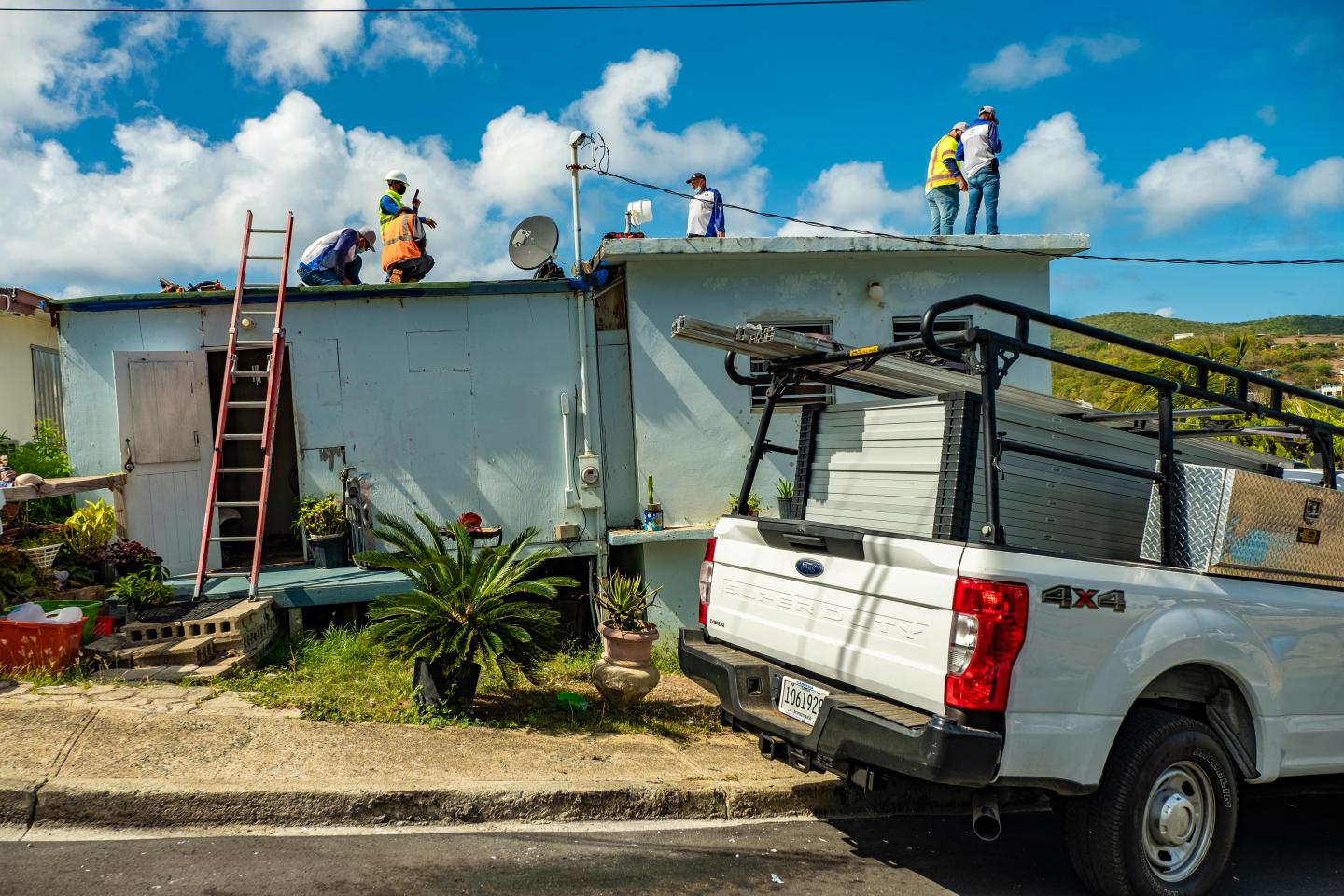 Workers installing solar panels on the roof of a small home