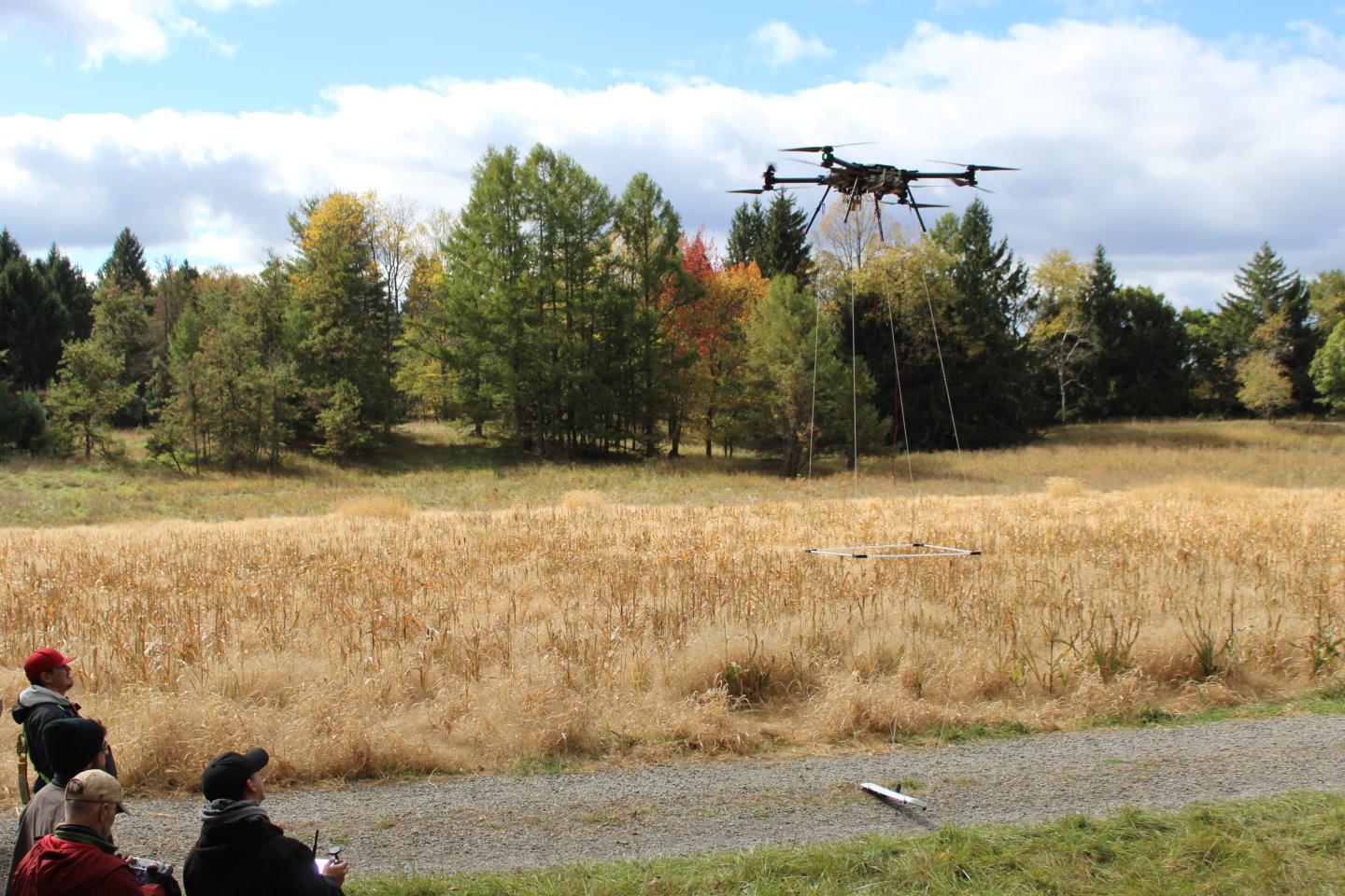 A group of onlookers watch a drone lifting into the sky