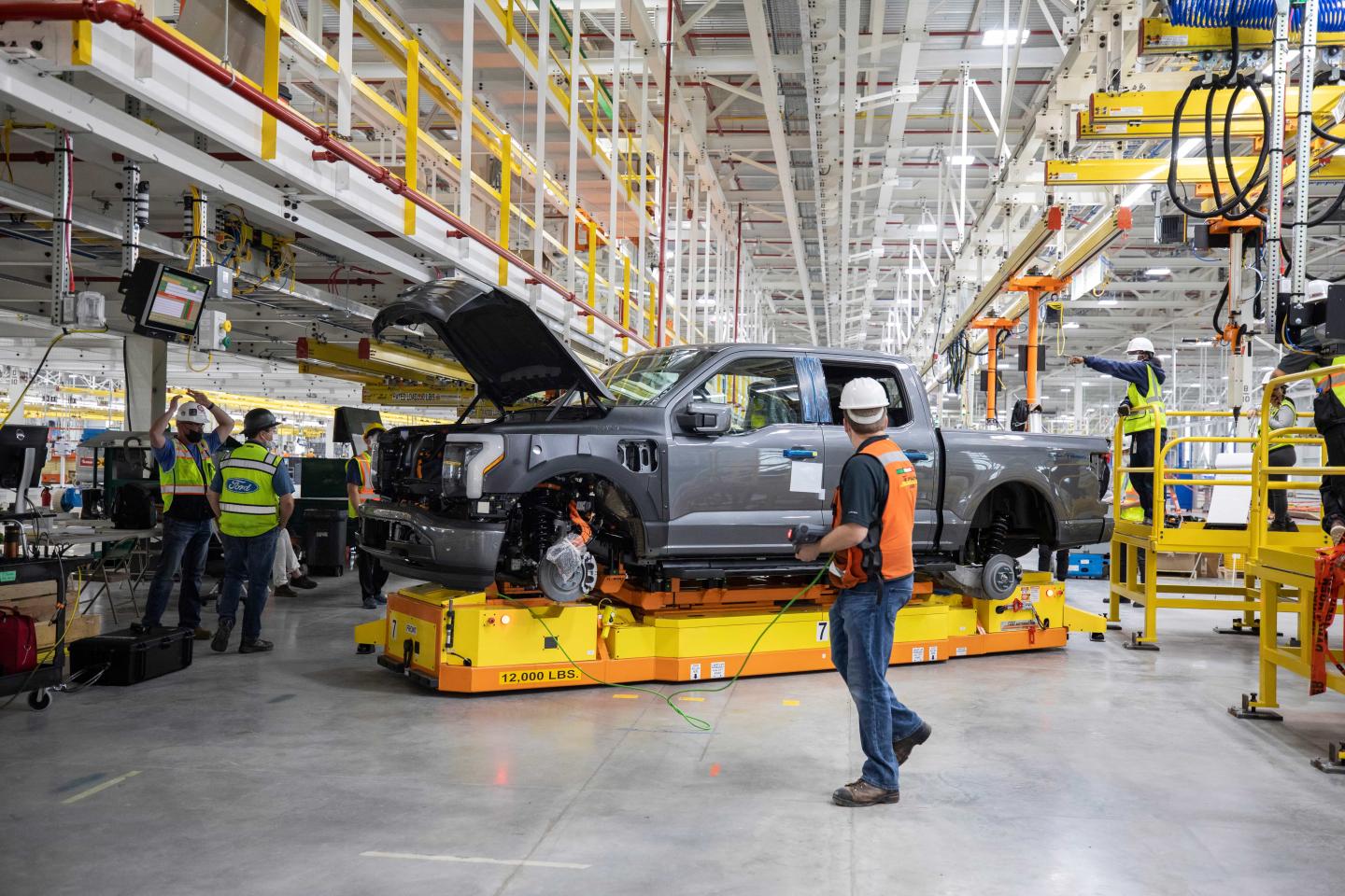 Workers standing nearby an electric truck being built