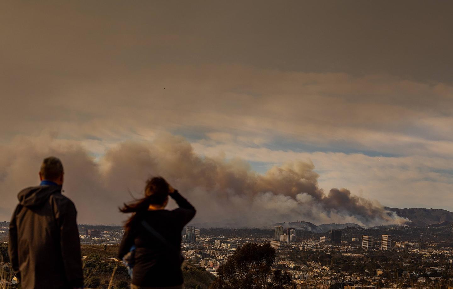 People looking at a plume of smoke in a California wildfire