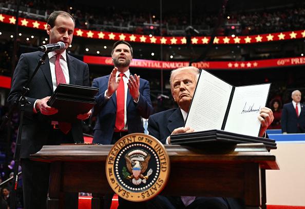 Donald Trump signing an executive order with JD Vance applauding behind him