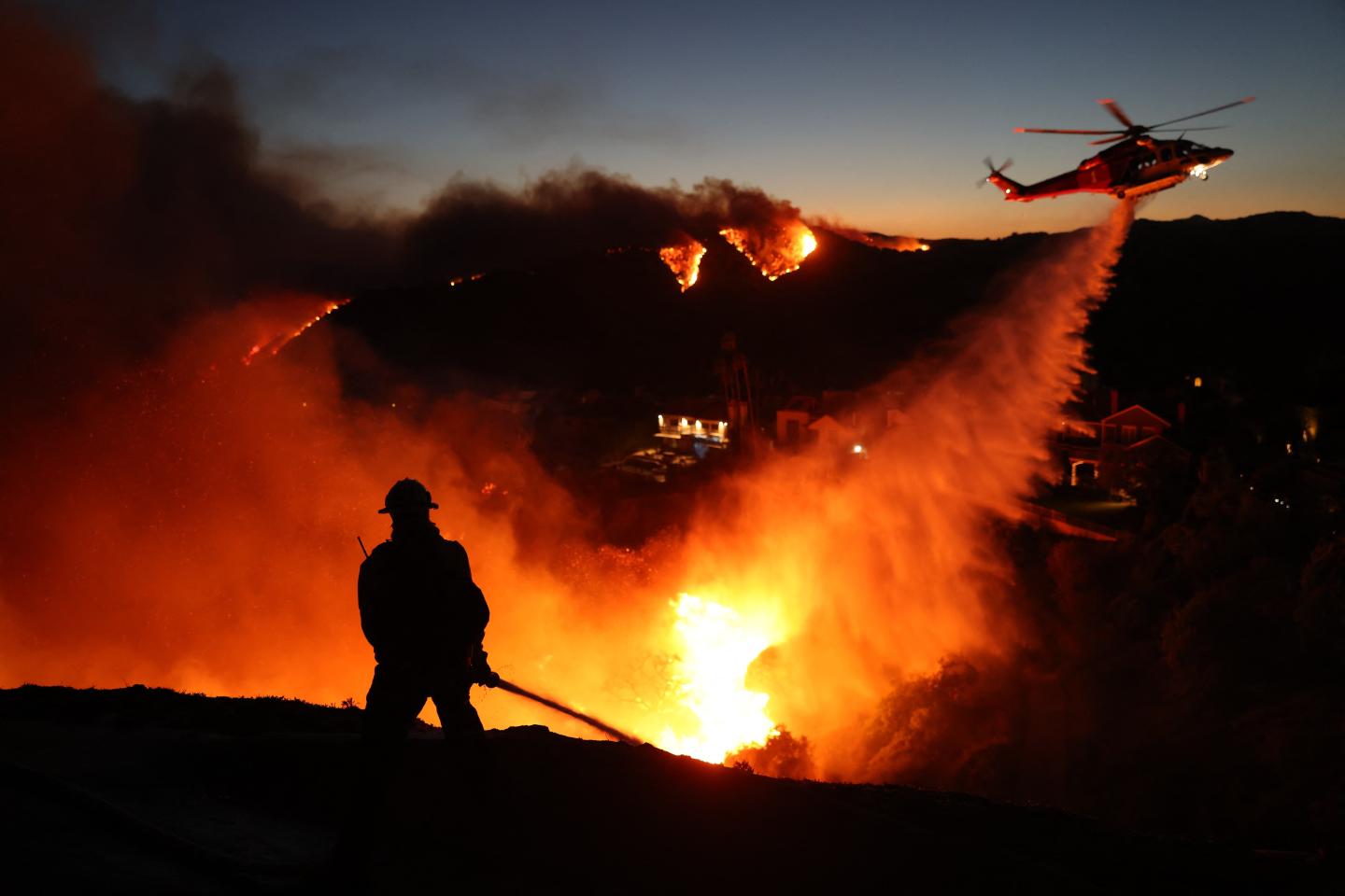 A firefighter and a helicopter fighting a wildfire in Los Angeles