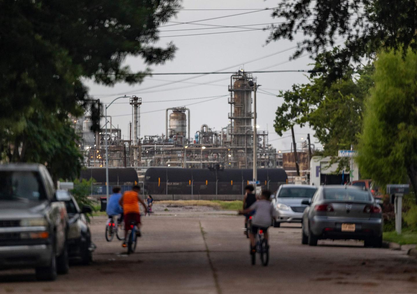 Kids riding bikes down a street with a power plant in the background