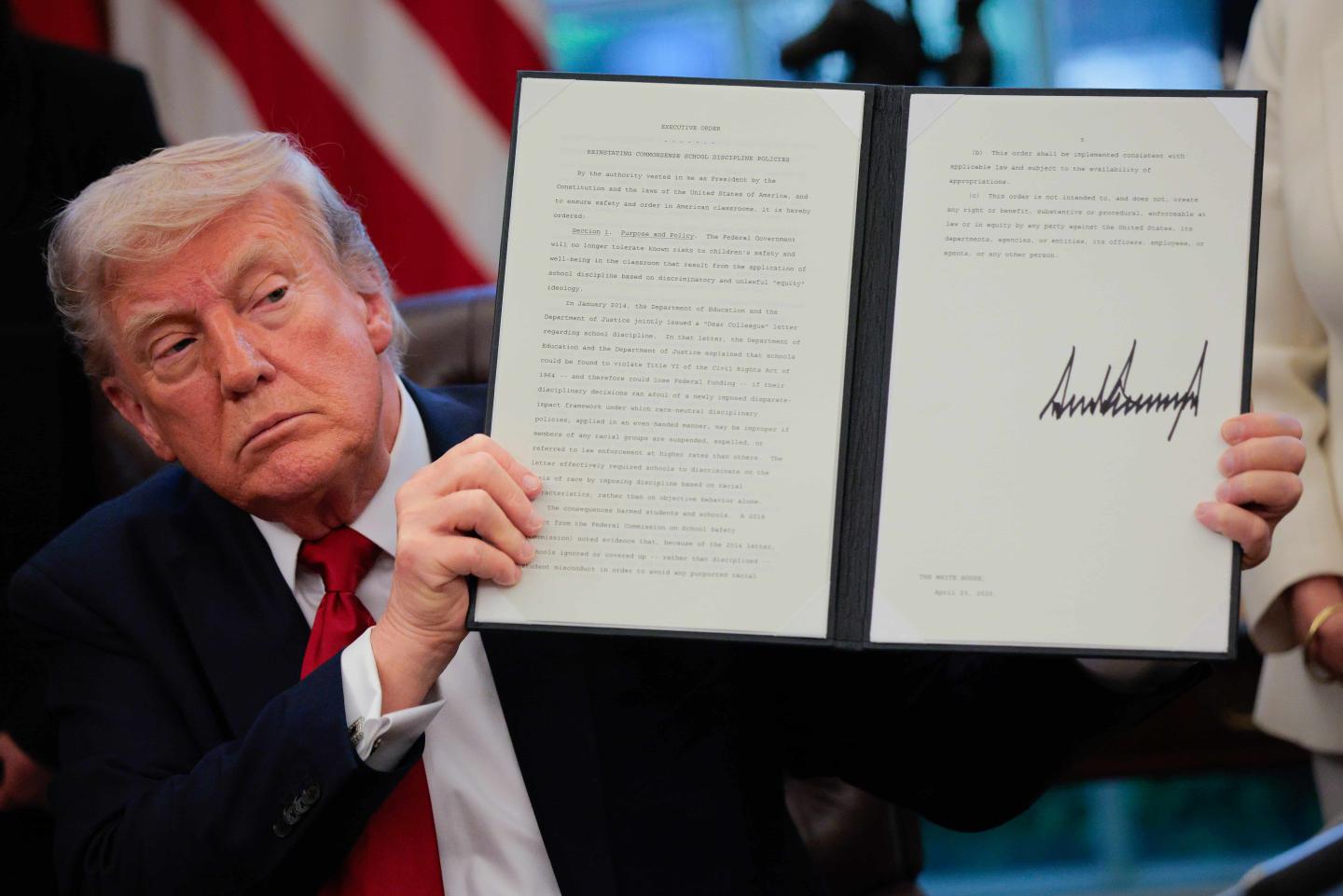 Donald Trump holding up an executive order he has signed