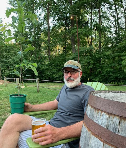 Tristan Shaw, holding a beer in one hand and his emotional support tree in the other