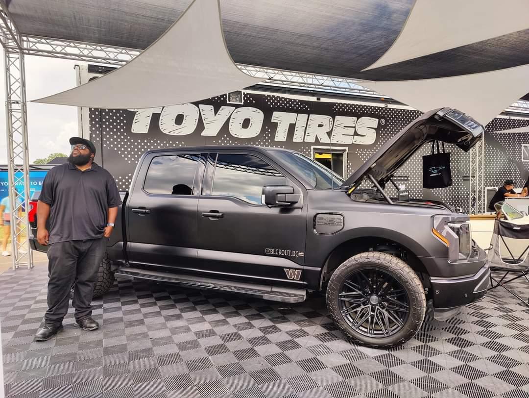 Michael Cowan standing on a stage in front of his Ford F-150 Lightning