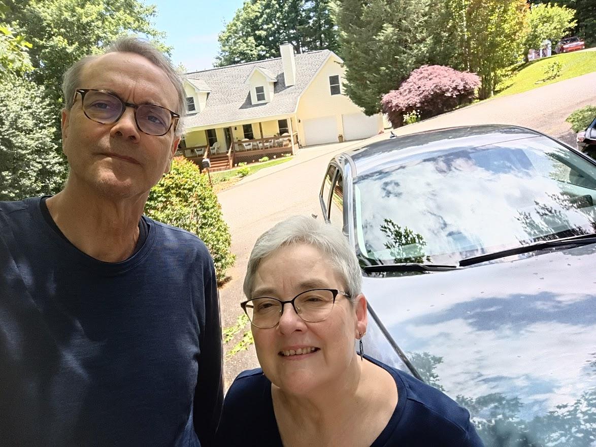 Glenn and Liz Peterson standing in front of their EV