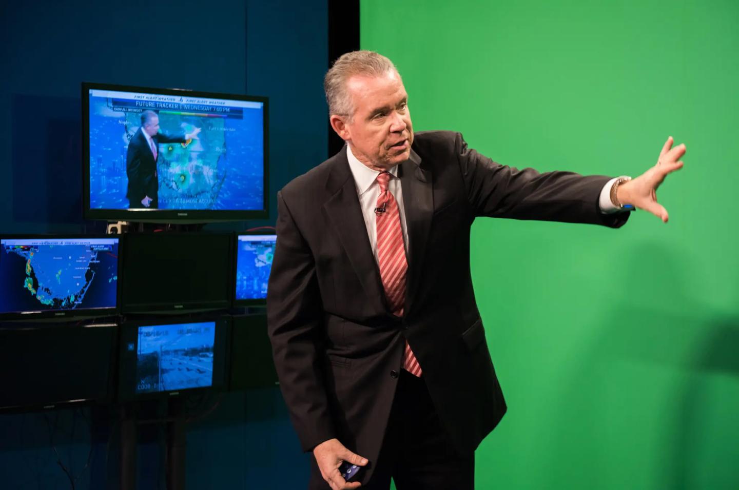 John Morales standing in front of a greenscreen doing the weather