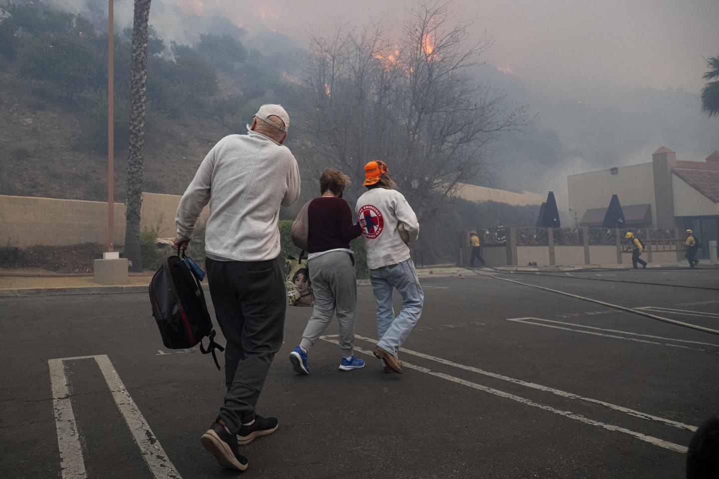Three people in hazy parking lot flee California wildfires