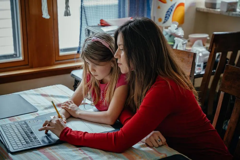 Lisa Lucas and her daughter sitting at a table working on a laptop