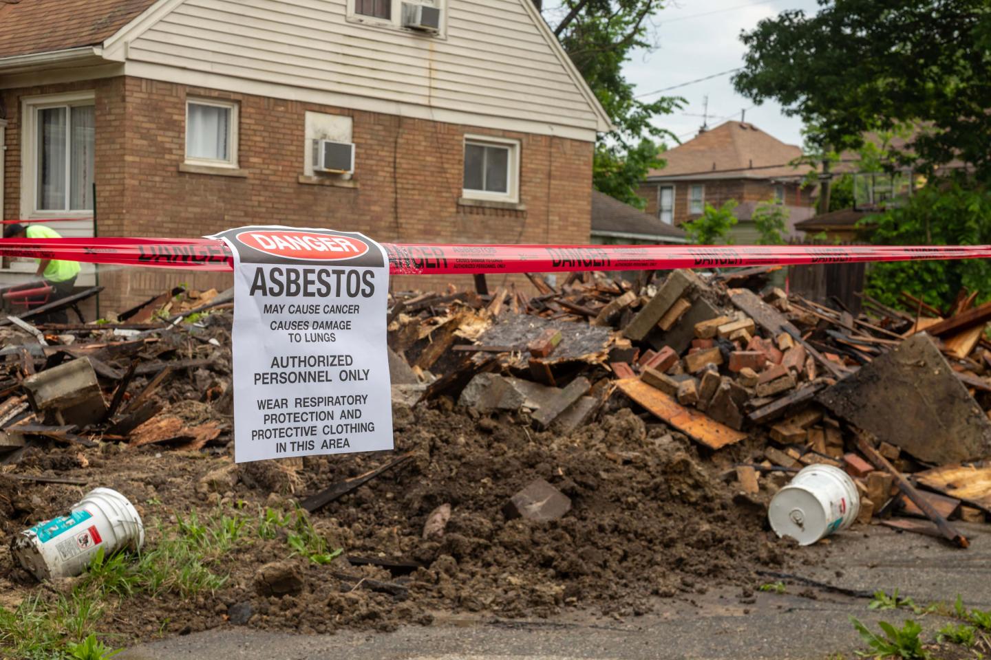 A red caution tape warning of asbestos