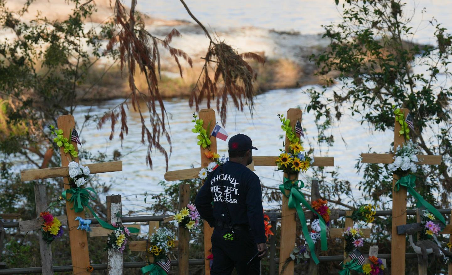 A firefighter stands in front of wooden crosses after the deadly Guadalupe River floods in Texas