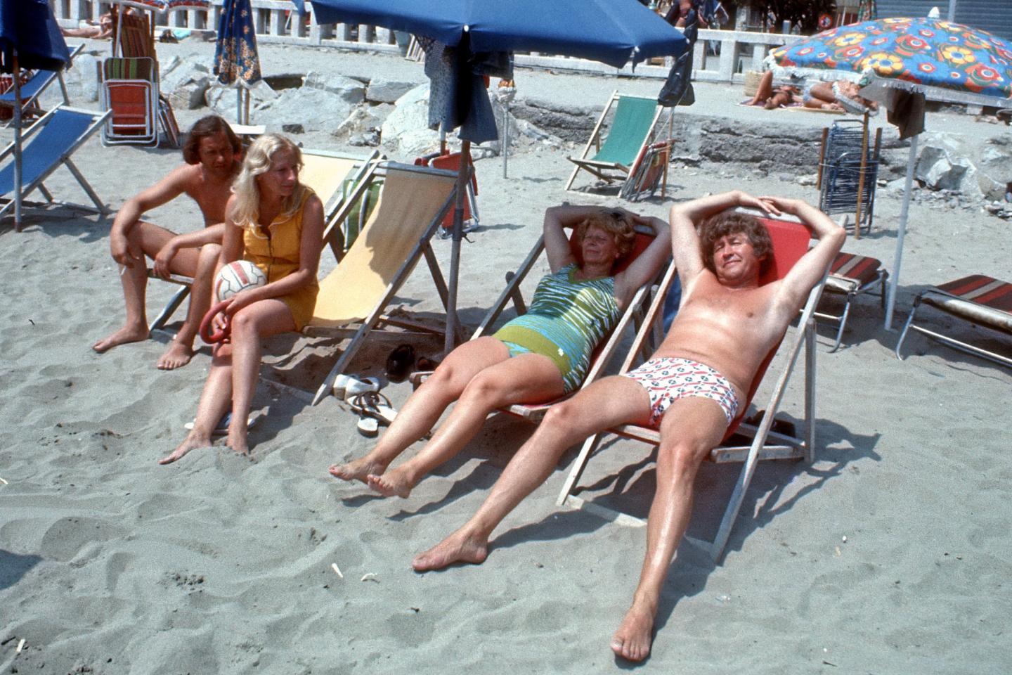A 1970s picture of four people sitting on beach chairs 