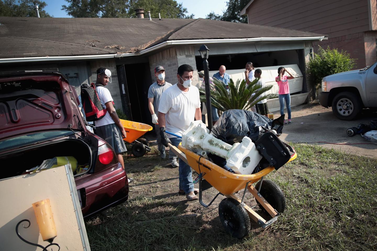 People hauling ruined items from a flooded house in a wheelbarrow