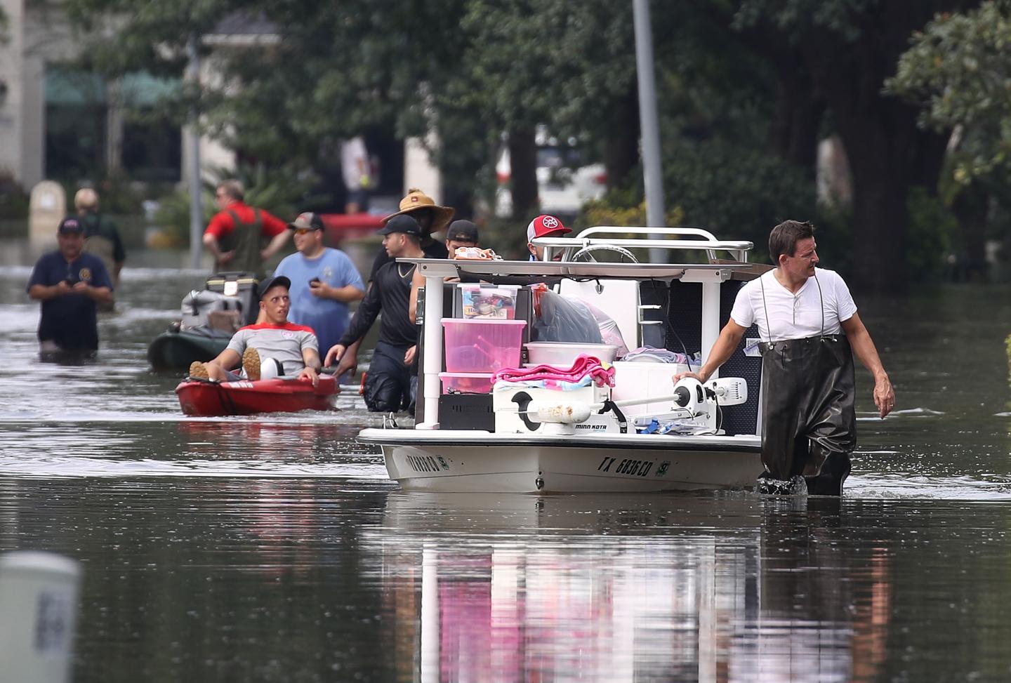 People pulling boats down the road after Hurricane Harvey flooded the streets