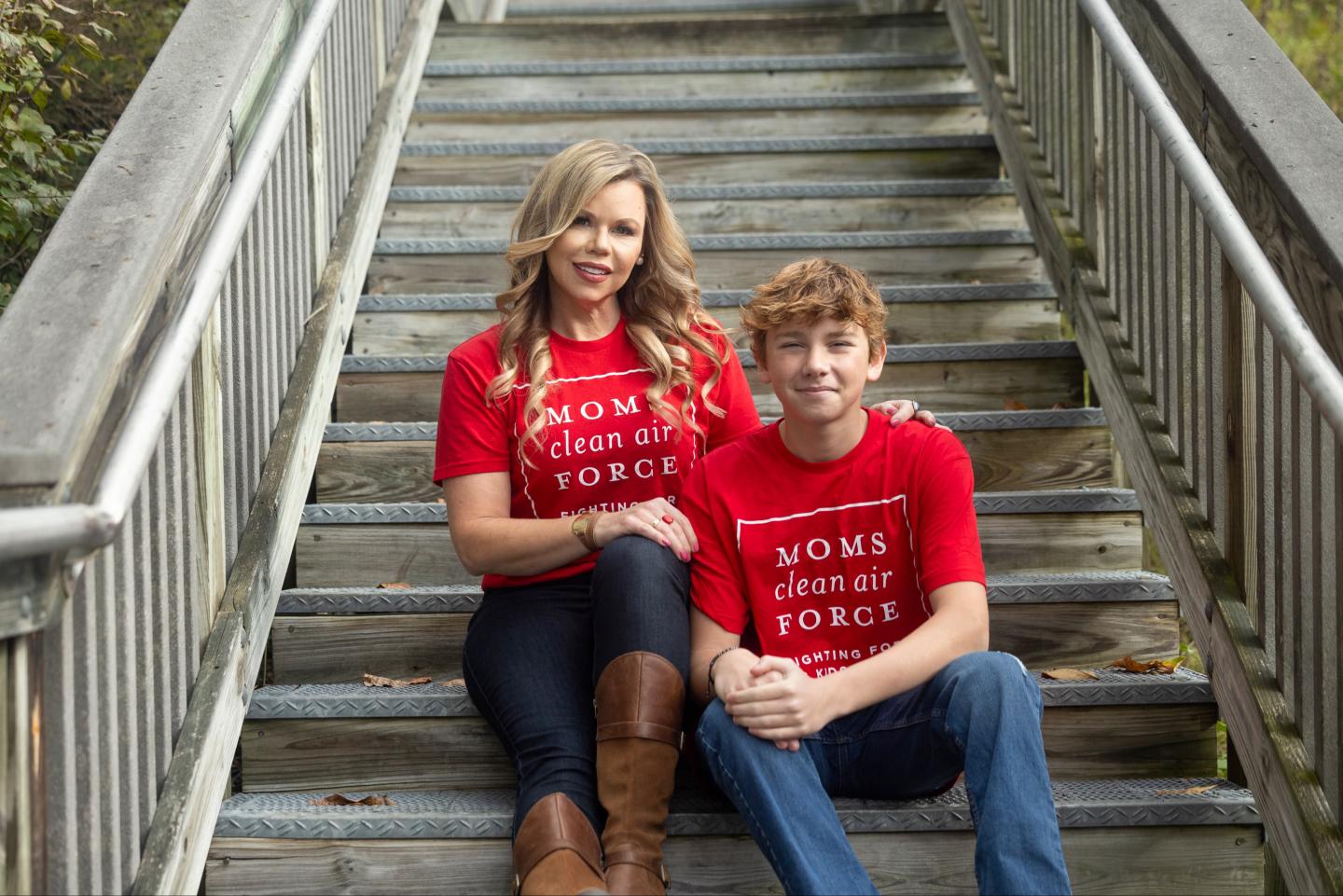 A mother and son sitting on steps wearing "Moms Clean Air Force" shirts