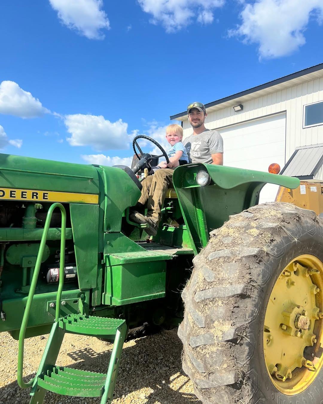 A man with his son sitting on his lap in a tractor