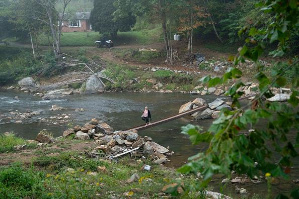 Woman walking across makeshift narrow bridge