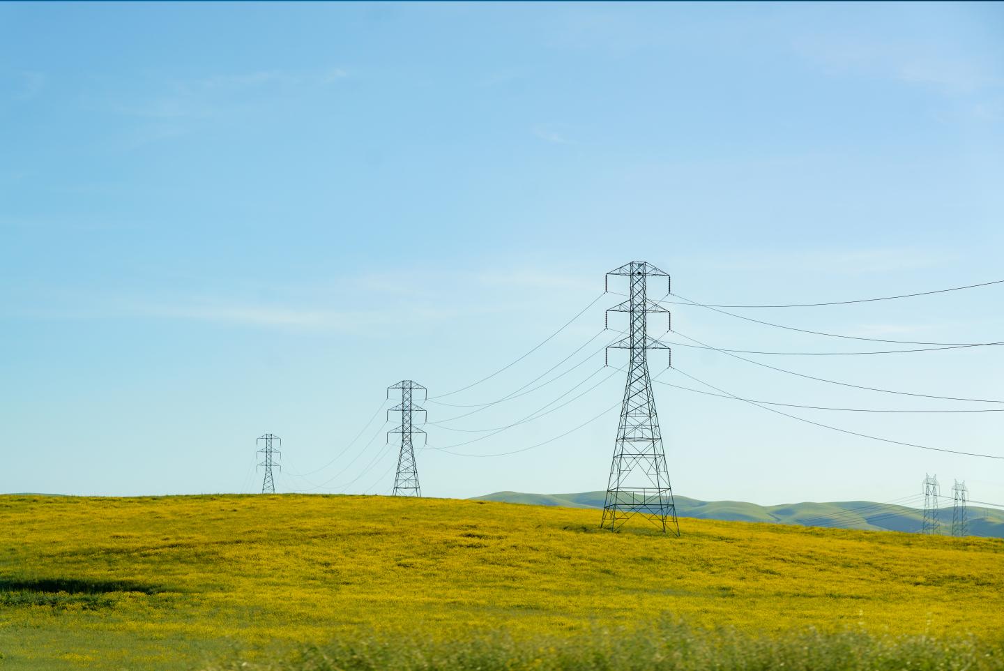 High tension lines cut across rolling hills near San Francisco, USA, weaving a modern energy network amidst the natural landscape.