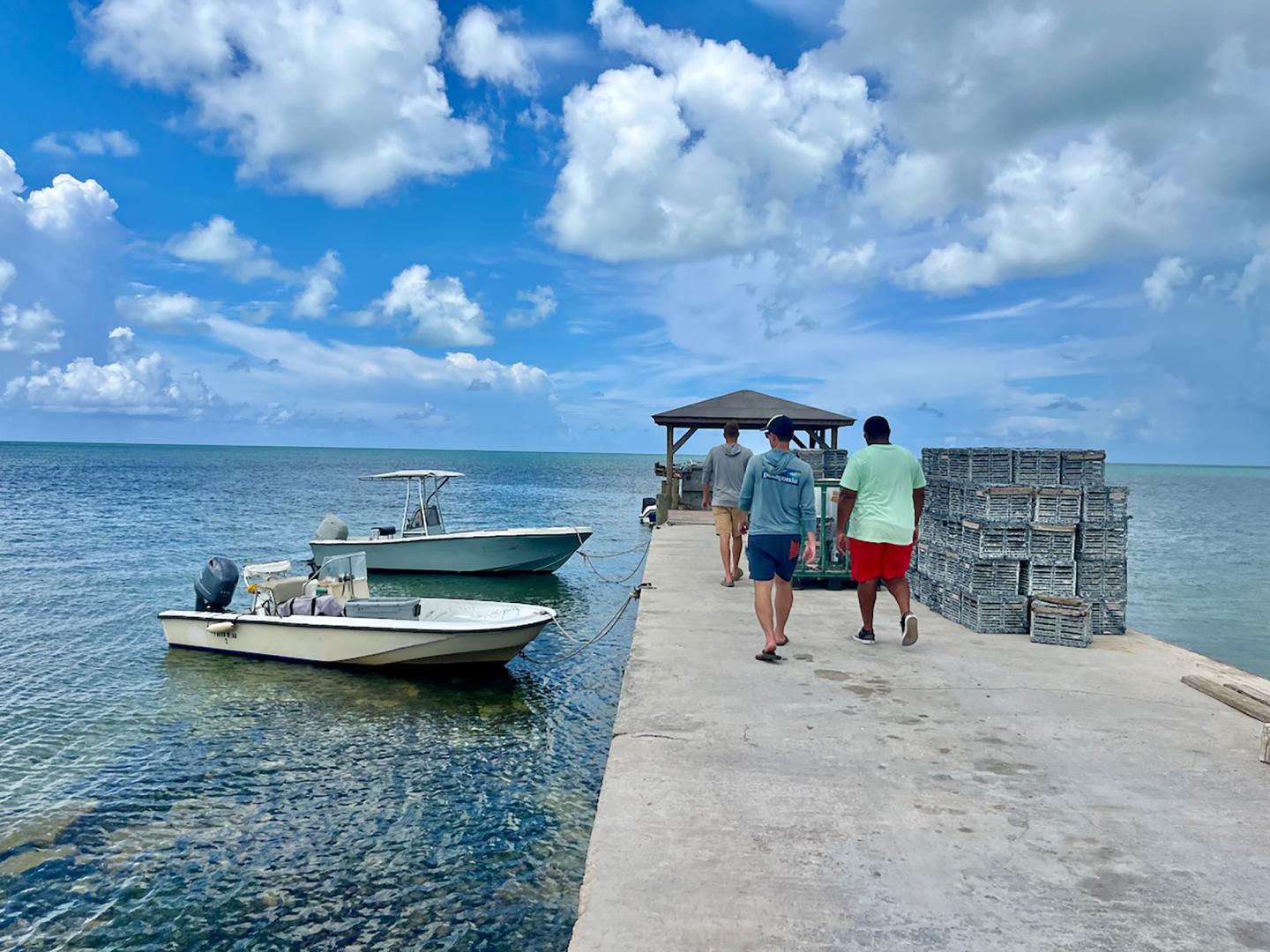 Group of men walking on a dock next to 2 docked boats