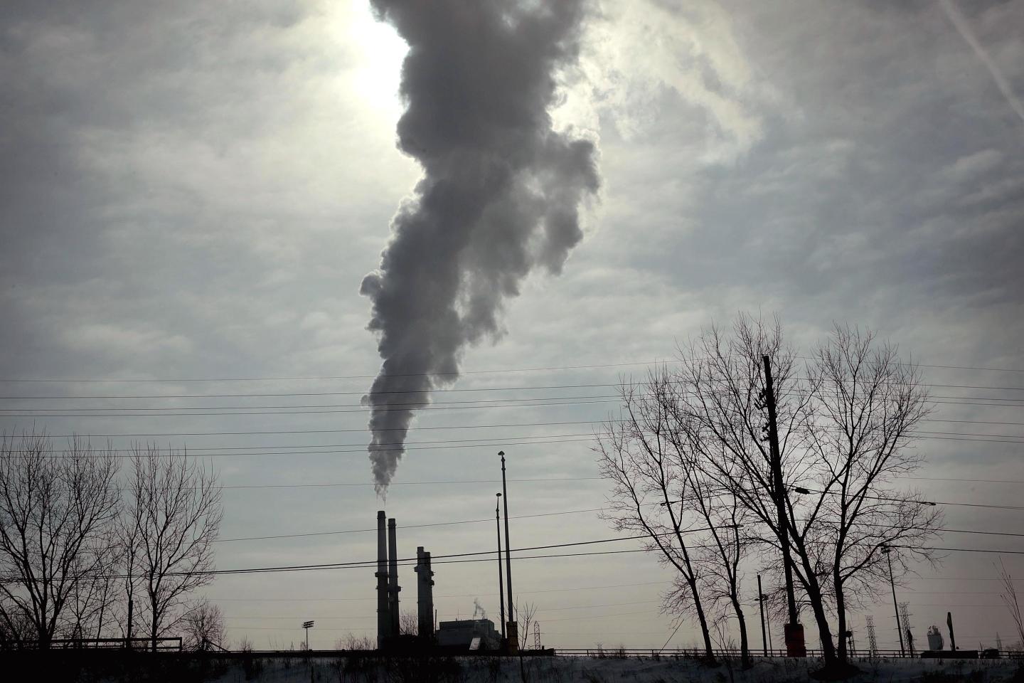 A plume of smoke blotting out the sun coming out of a coal power plant