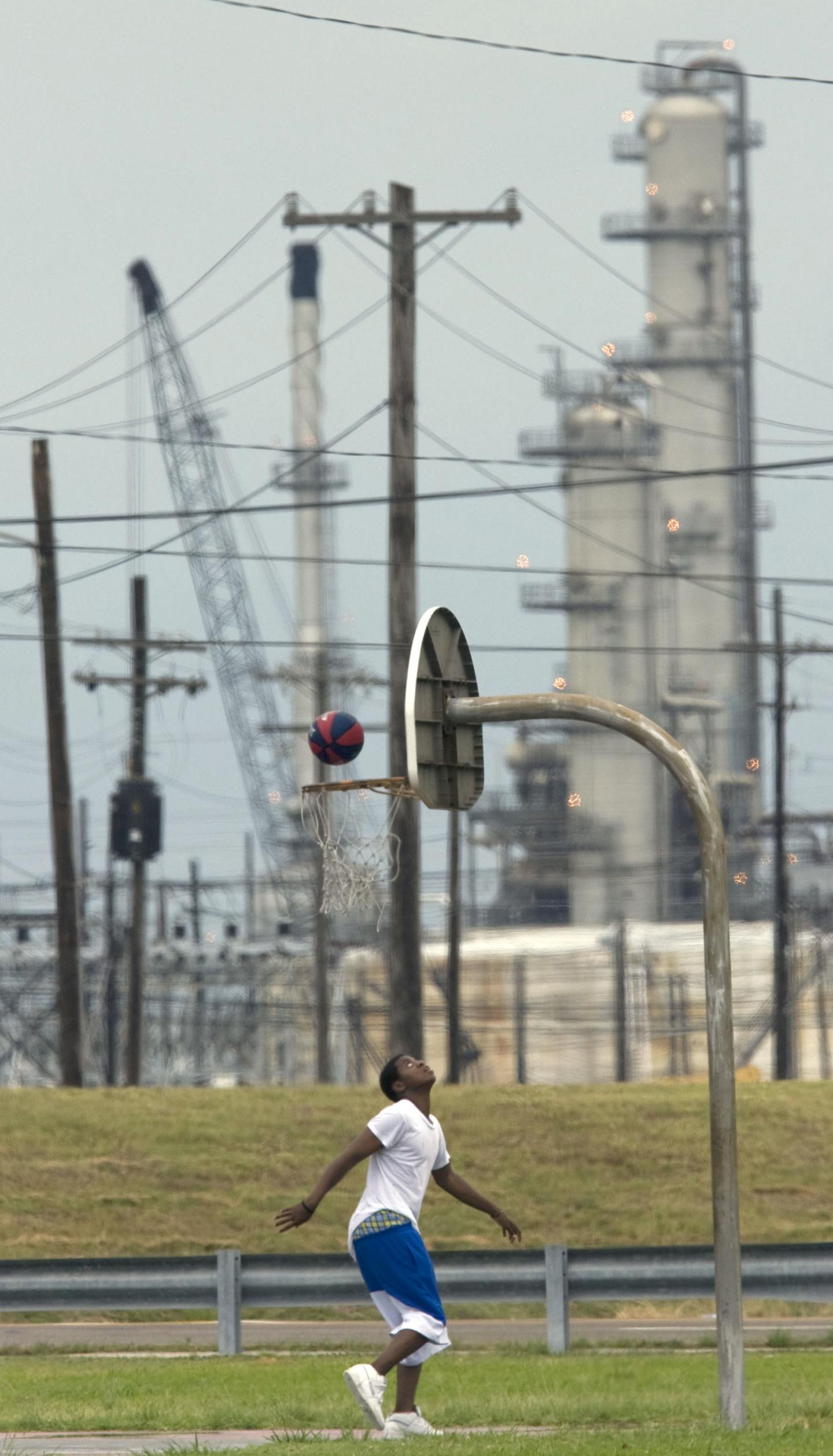 A young man playing basketball in front of a gas facility in New Orleans, Louisiana
