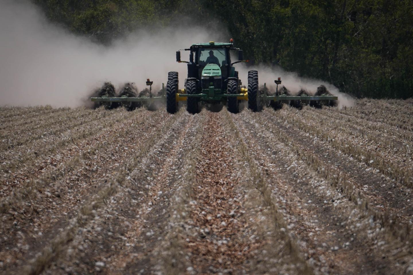 A tractor pulling a combine with large clouds of dust coming up behind it