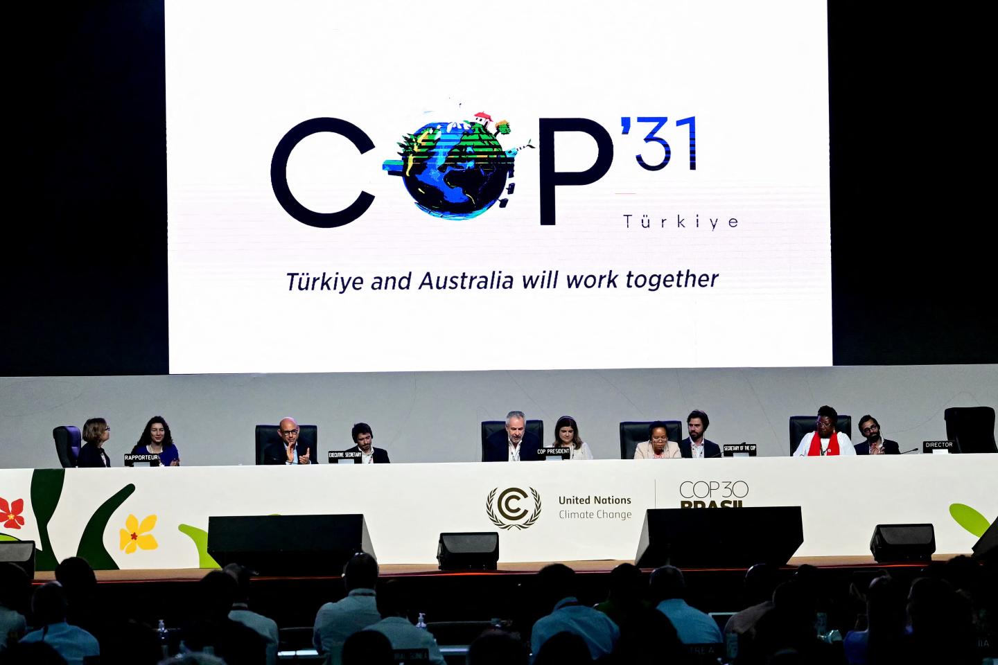 People sitting on stage under a COP31 banner highlighting next year's conference