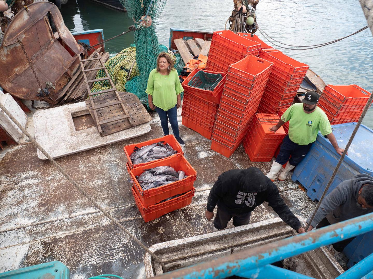 An overhead shot of fish being taken off a boat in orange containers