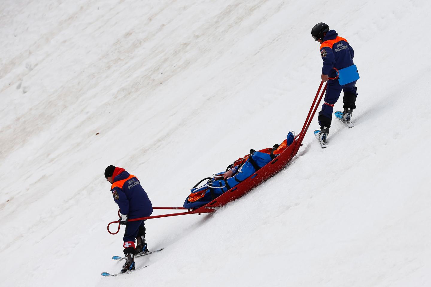 A hurt Olympian being brought down a slope on a sled