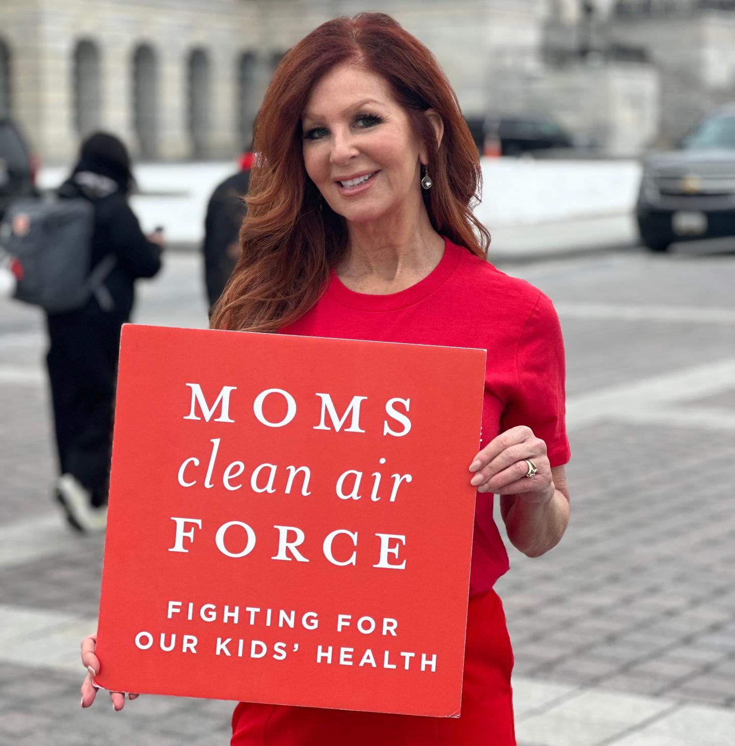 Jayne Black holding a sign that says Moms Clean Air Force fighting for our kids' health