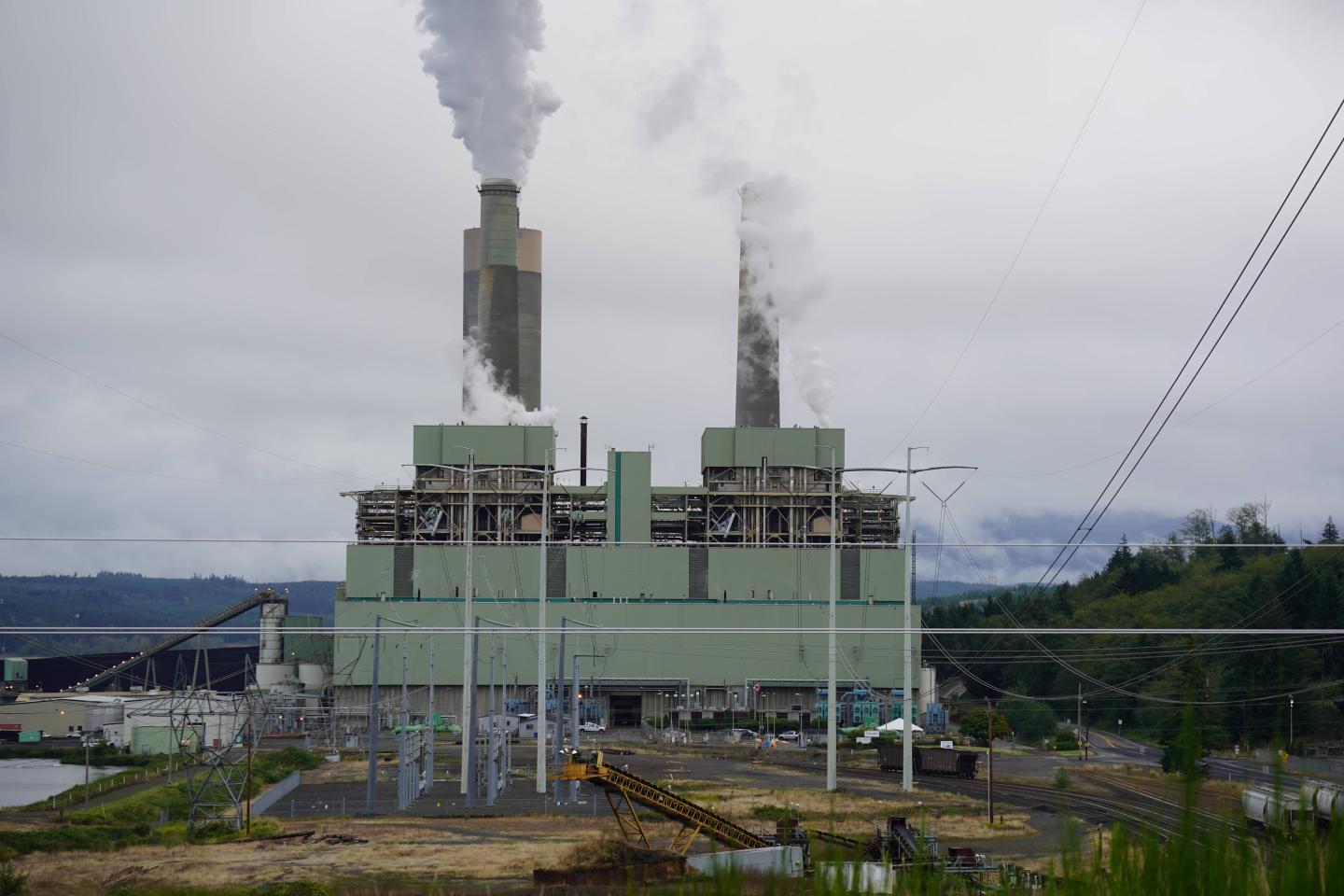 A coal power plant with smoke coming out of its smokestacks 