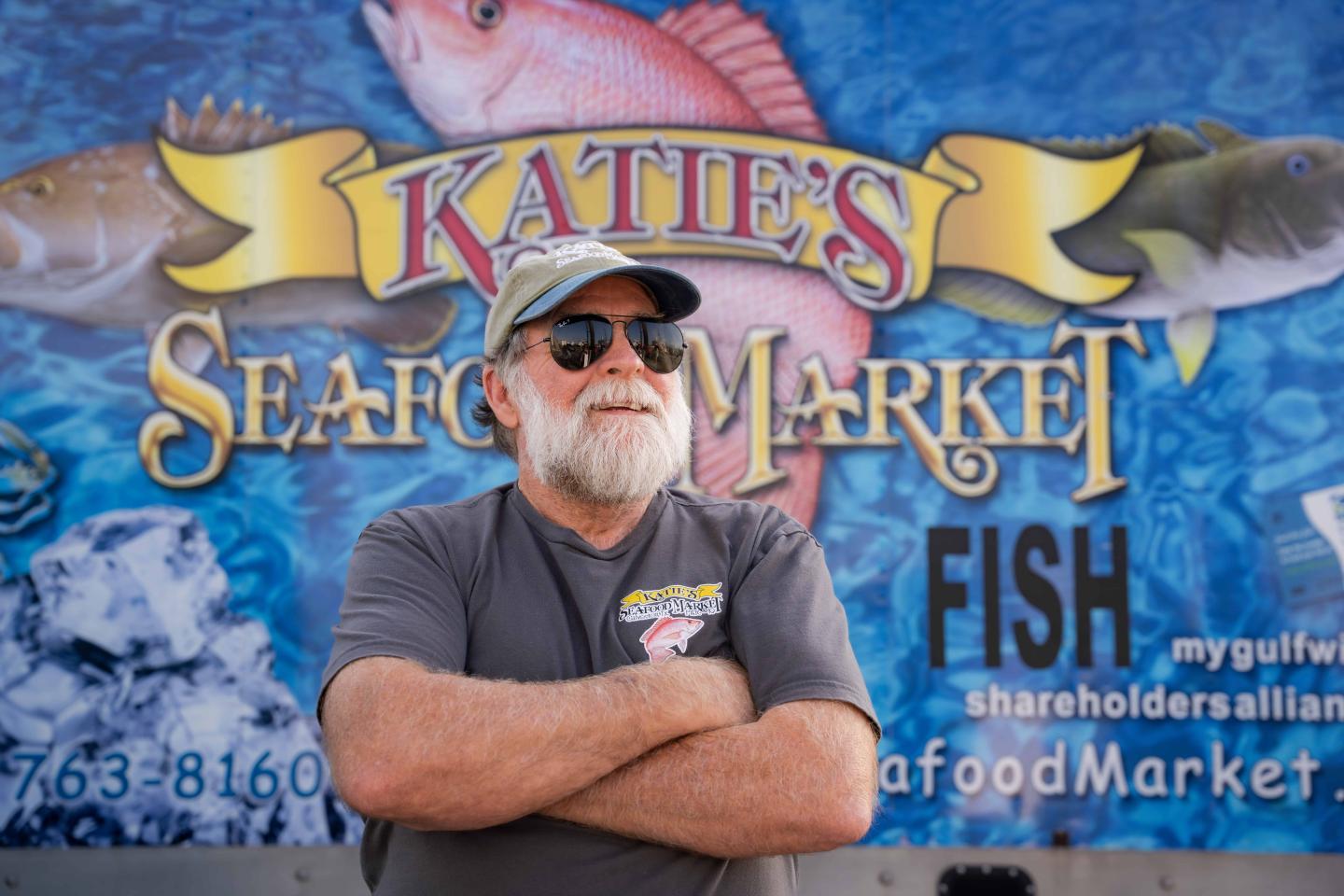 Fisherman Buddy Guindon standing in front of a Katie's Seafood Market mural