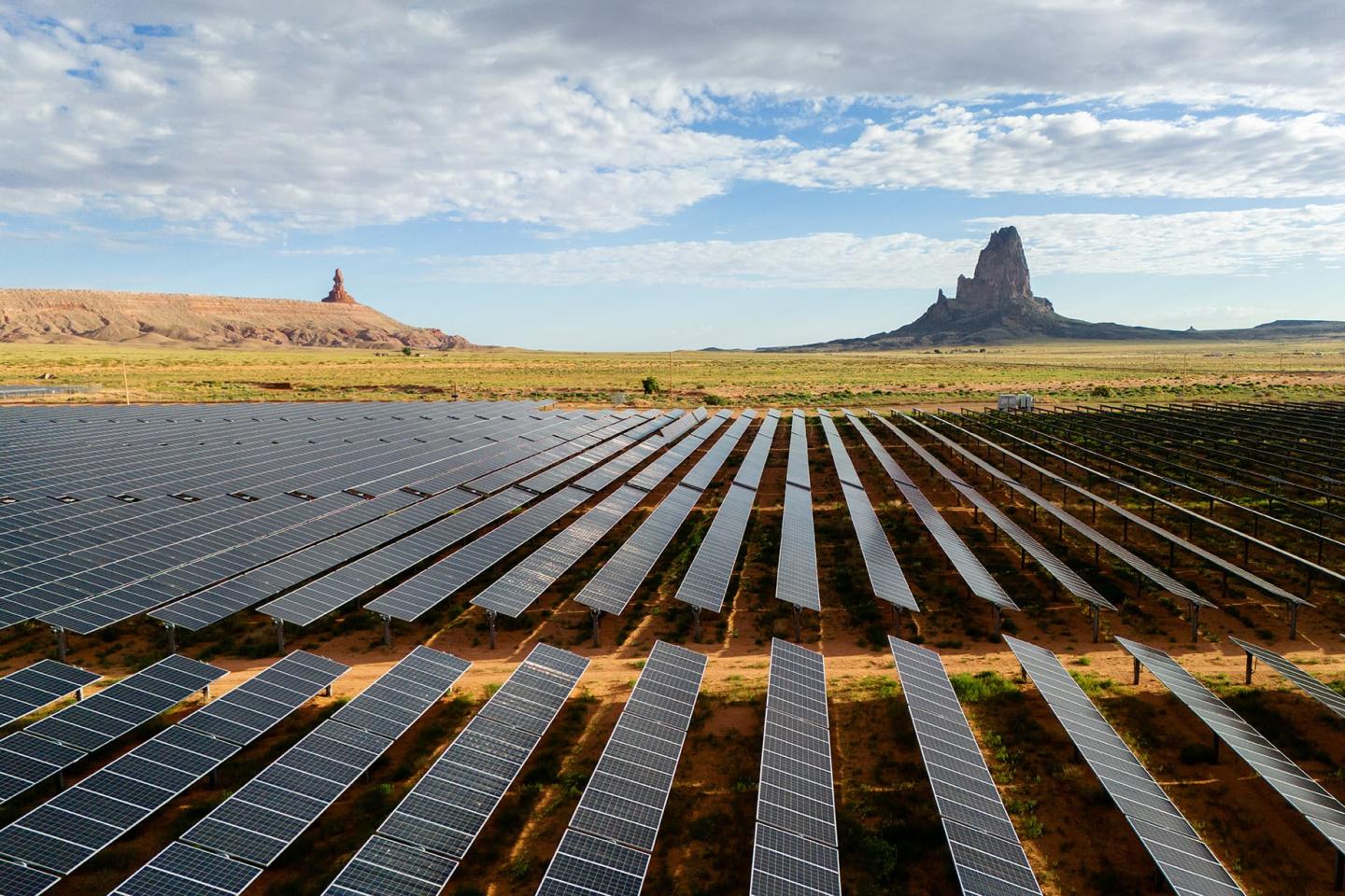 Rows of solar panels in Arizona with large mountainous rock formations in the far background