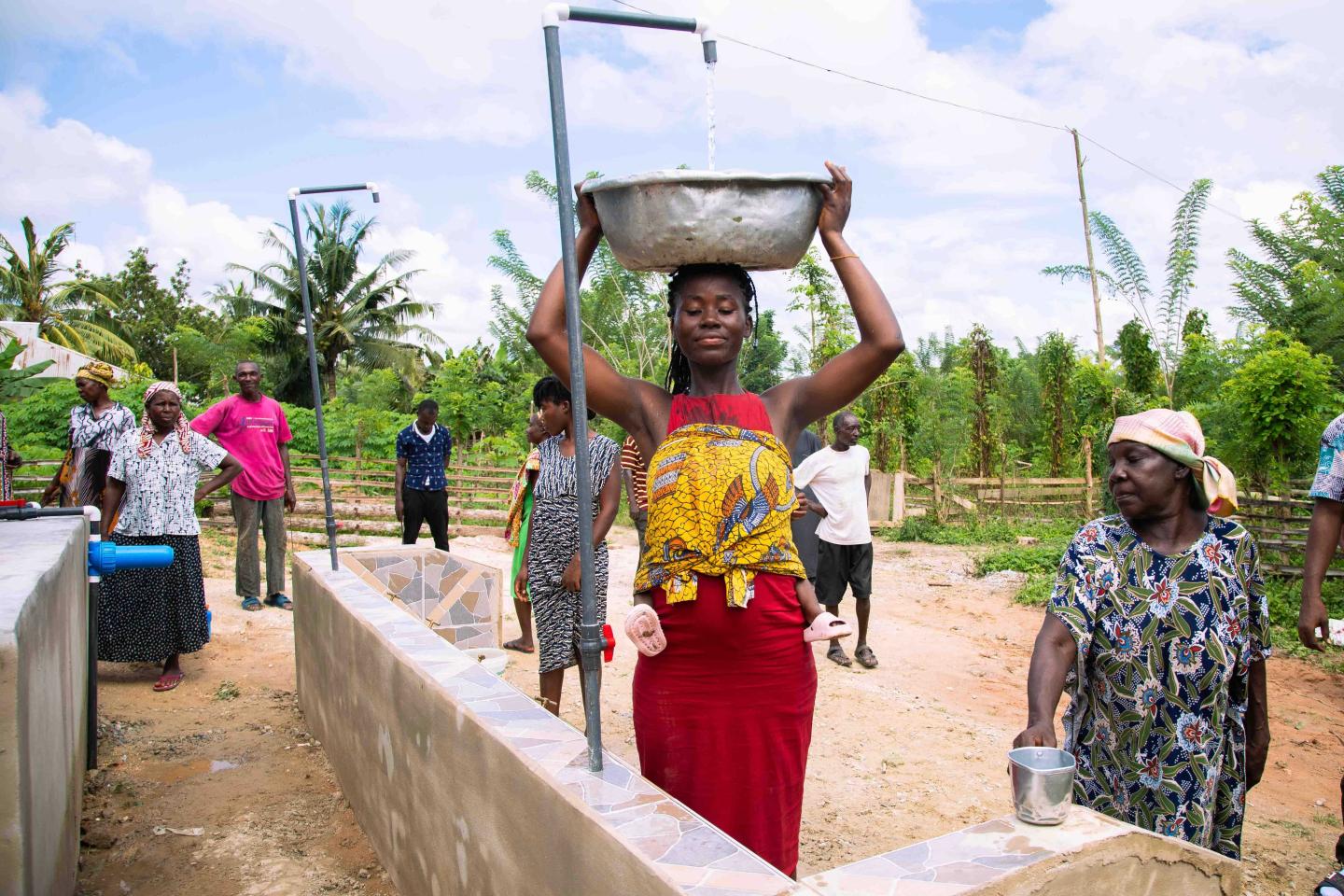 A woman holdin a bowl on her head as it is filled with water