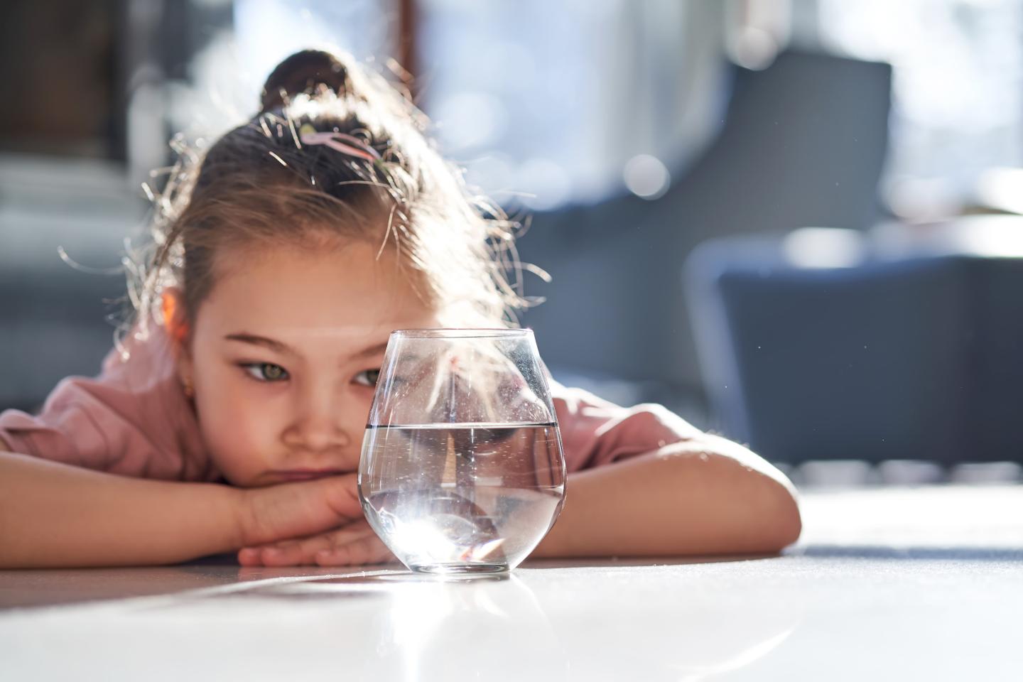 A small child looking at a glass of water