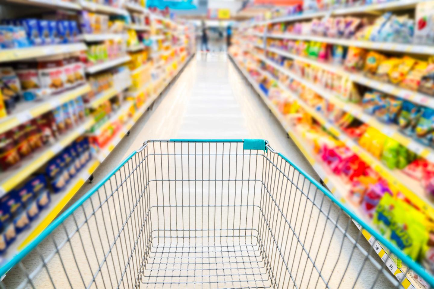 A shopping cart going down a colorful aisle at the grocery store