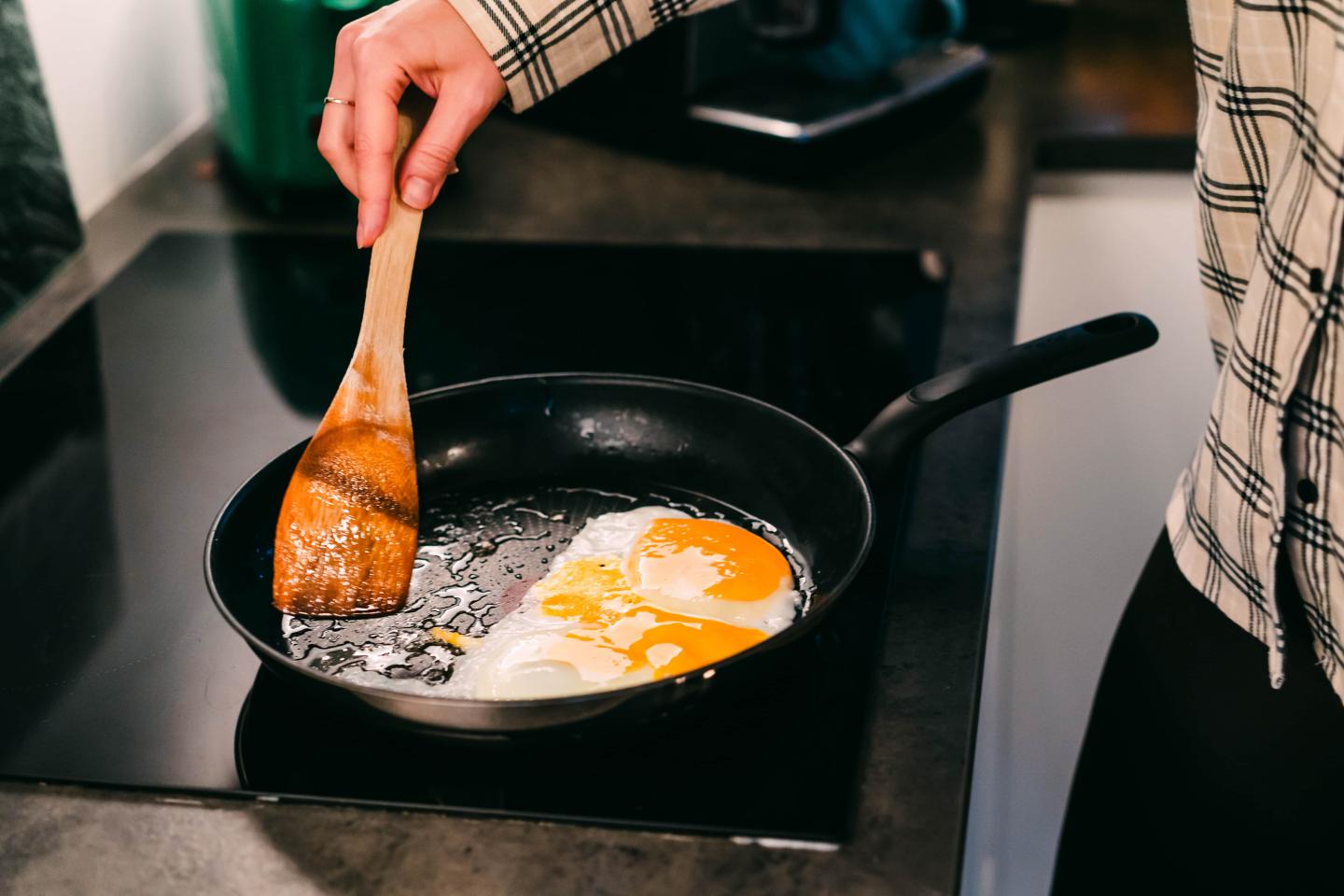 Someone cooking eggs in a skillet with a wooden spatula